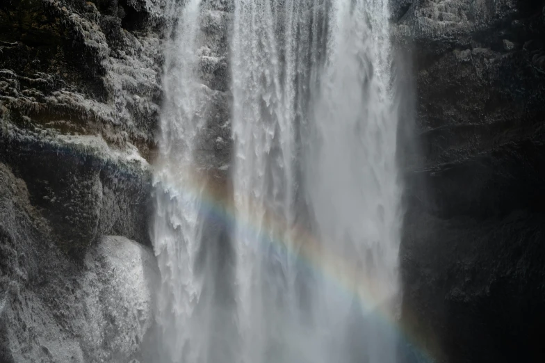 a rainbow sits beneath the waterfall in the dark