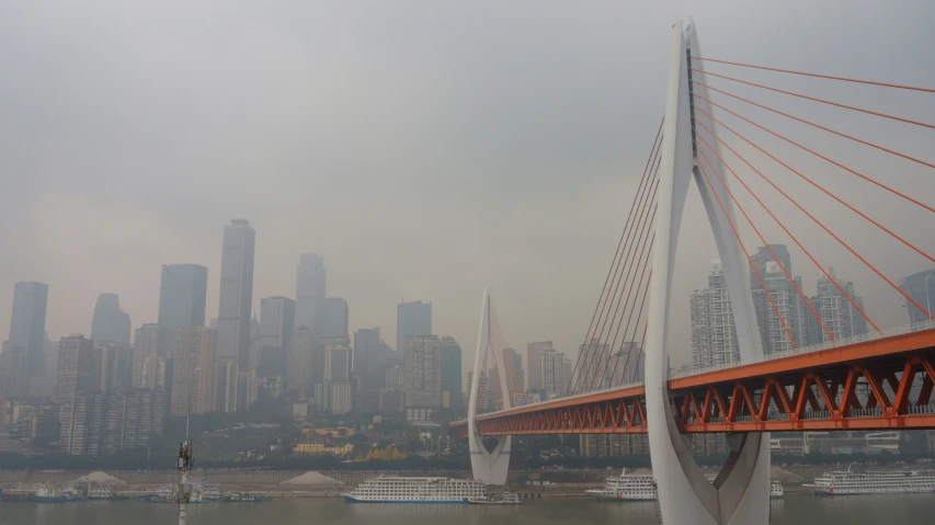 the top of a tall bridge with a very tall city in the background