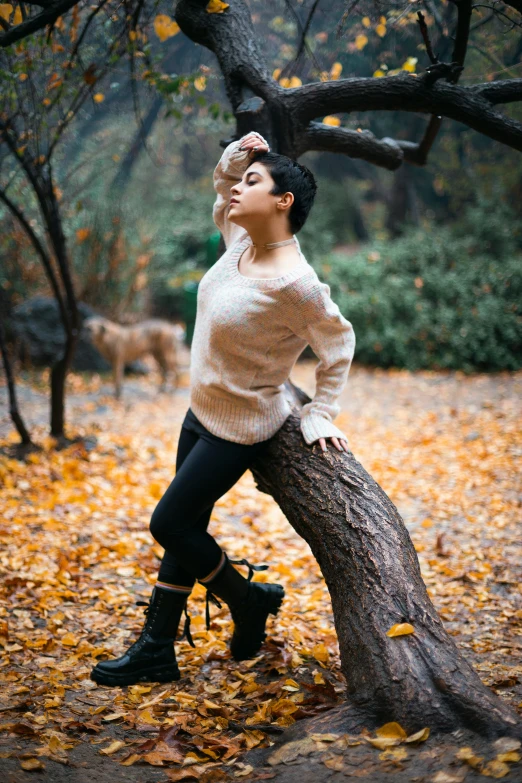 woman posing on fallen autumn leaves in park setting