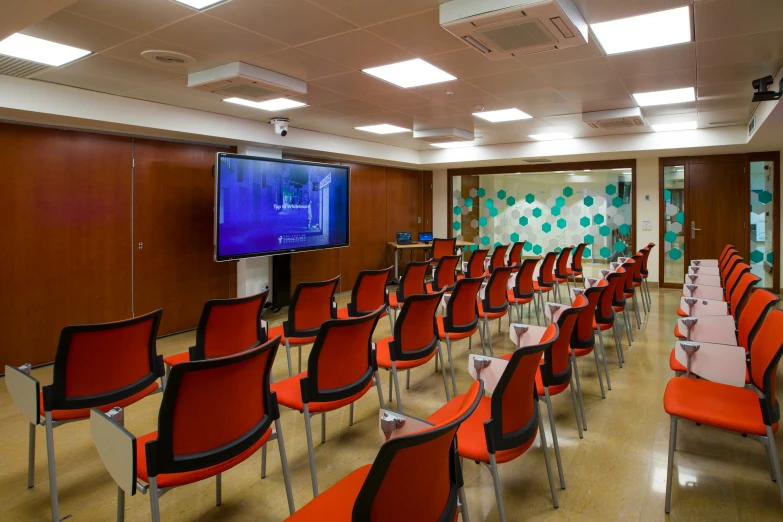 a room with several rows of chairs and a flat screen tv mounted to the wall