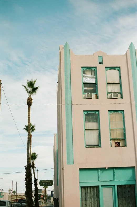 a tall palm tree sitting next to a building on a street