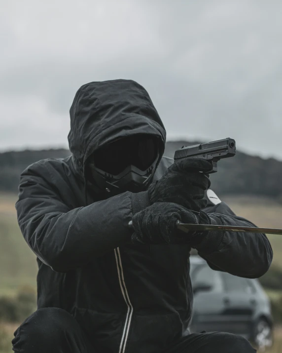 a man in a black jacket aiming a rifle