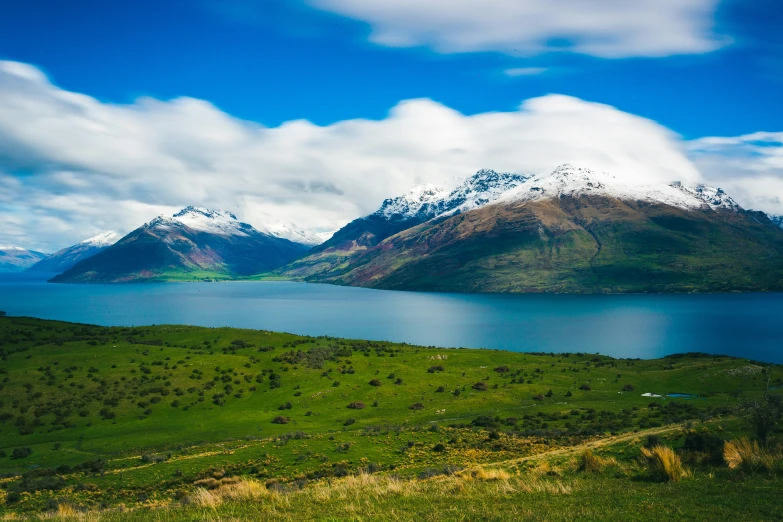 the snow - capped mountain are behind the lake