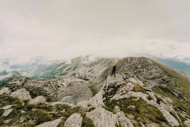 a person standing on top of a mountain near a lake