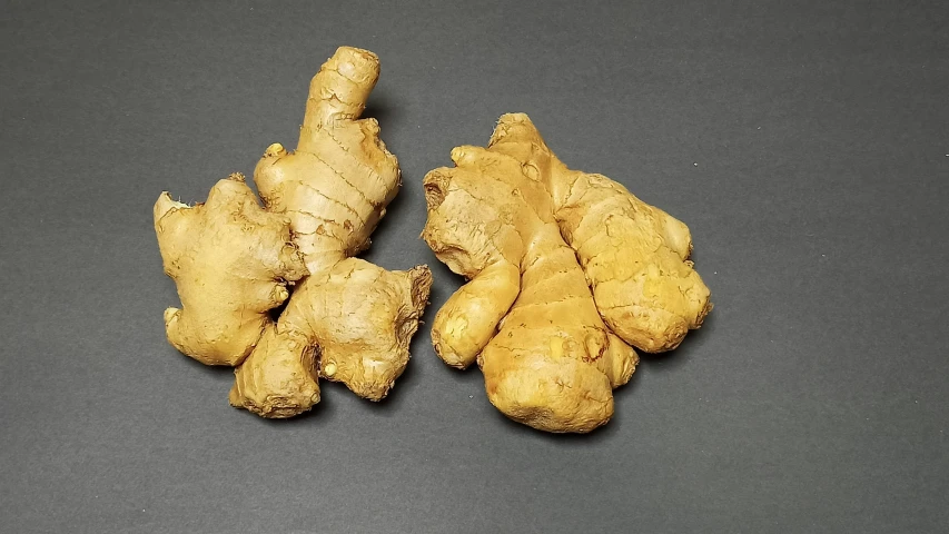 two pieces of ginger sit next to a bunch of cut ginger