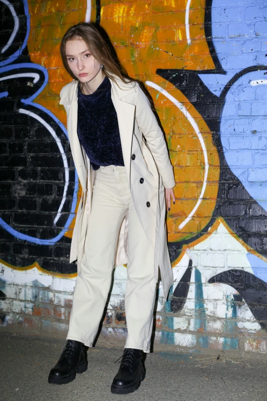 a woman is wearing all black while leaning against a brick wall