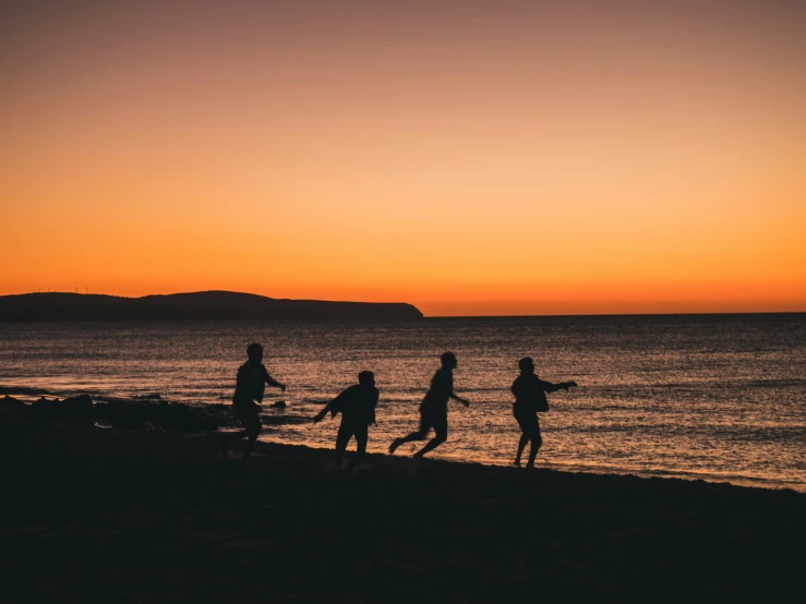 people standing on top of a beach near the ocean