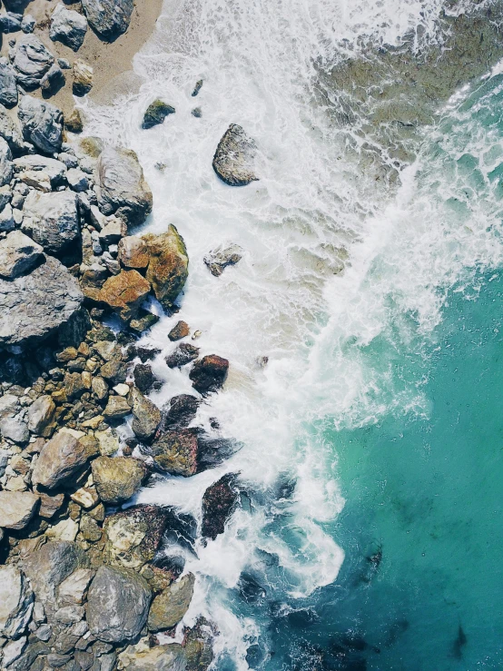 an aerial view of an ocean with waves crashing on shore