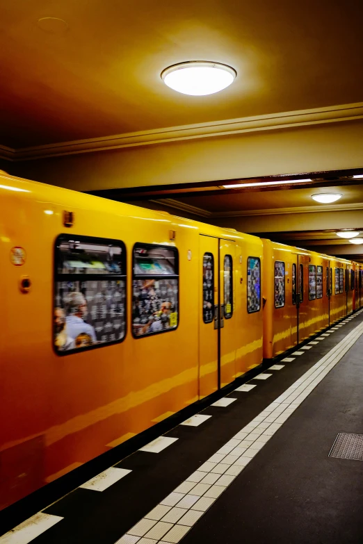 a large orange train is passing by several people