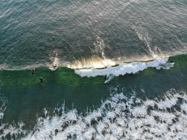 two people ride surfboards on top of green water