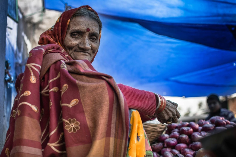 an older woman stands in front of a bunch of produce