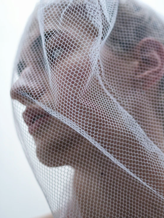 a woman wearing a veil is looking through the net