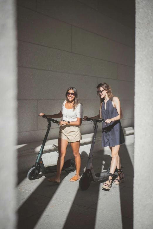 a pair of women standing by a scooter