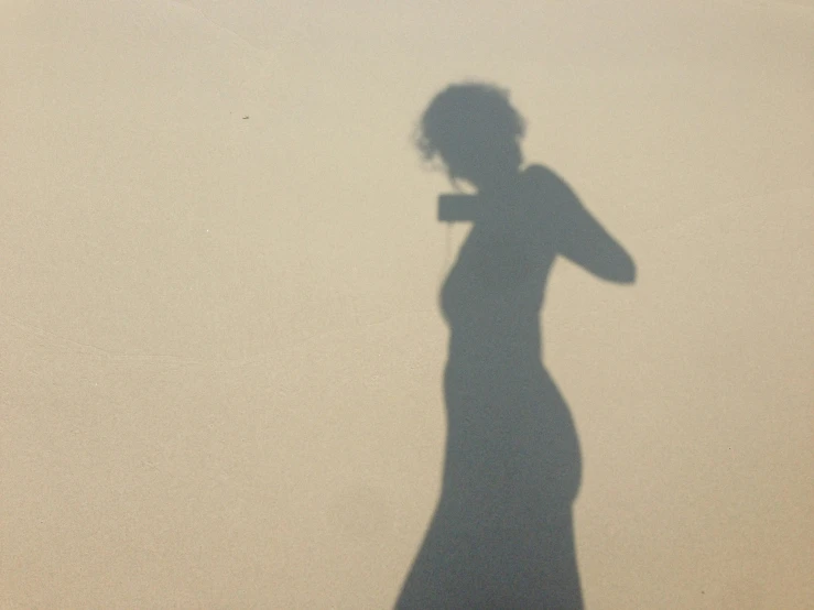 a shadow of a woman holding up a umbrella