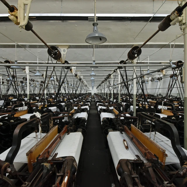 many rows of fabric looms sit on poles in an industrial warehouse