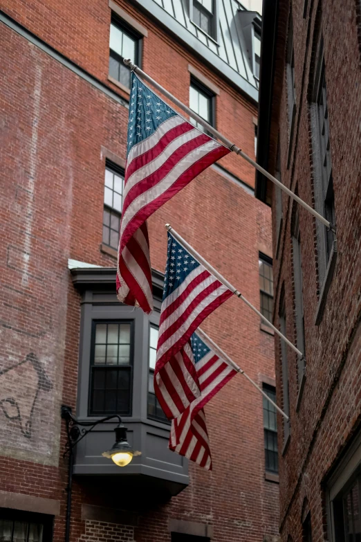 two american flags in front of a brick building