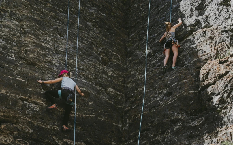 two climbers climbing up a very steep rocky wall