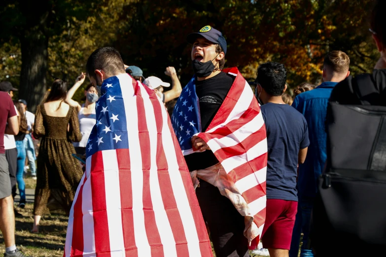 a man is holding a large american flag in a crowd