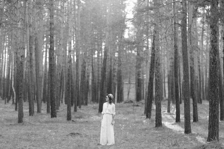 black and white pograph of woman standing in front of pine trees