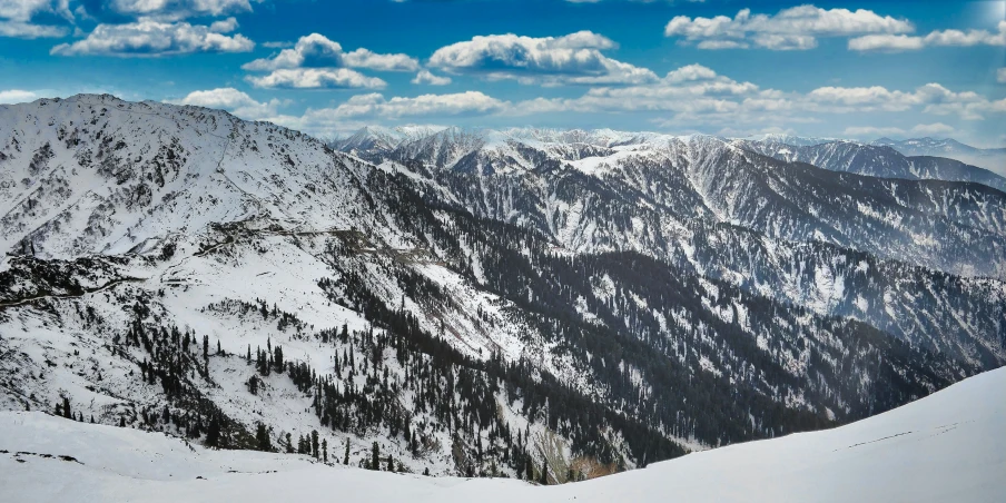 the mountains are covered in snow under a blue cloudy sky