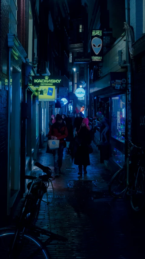 people walking down a street under a dark light