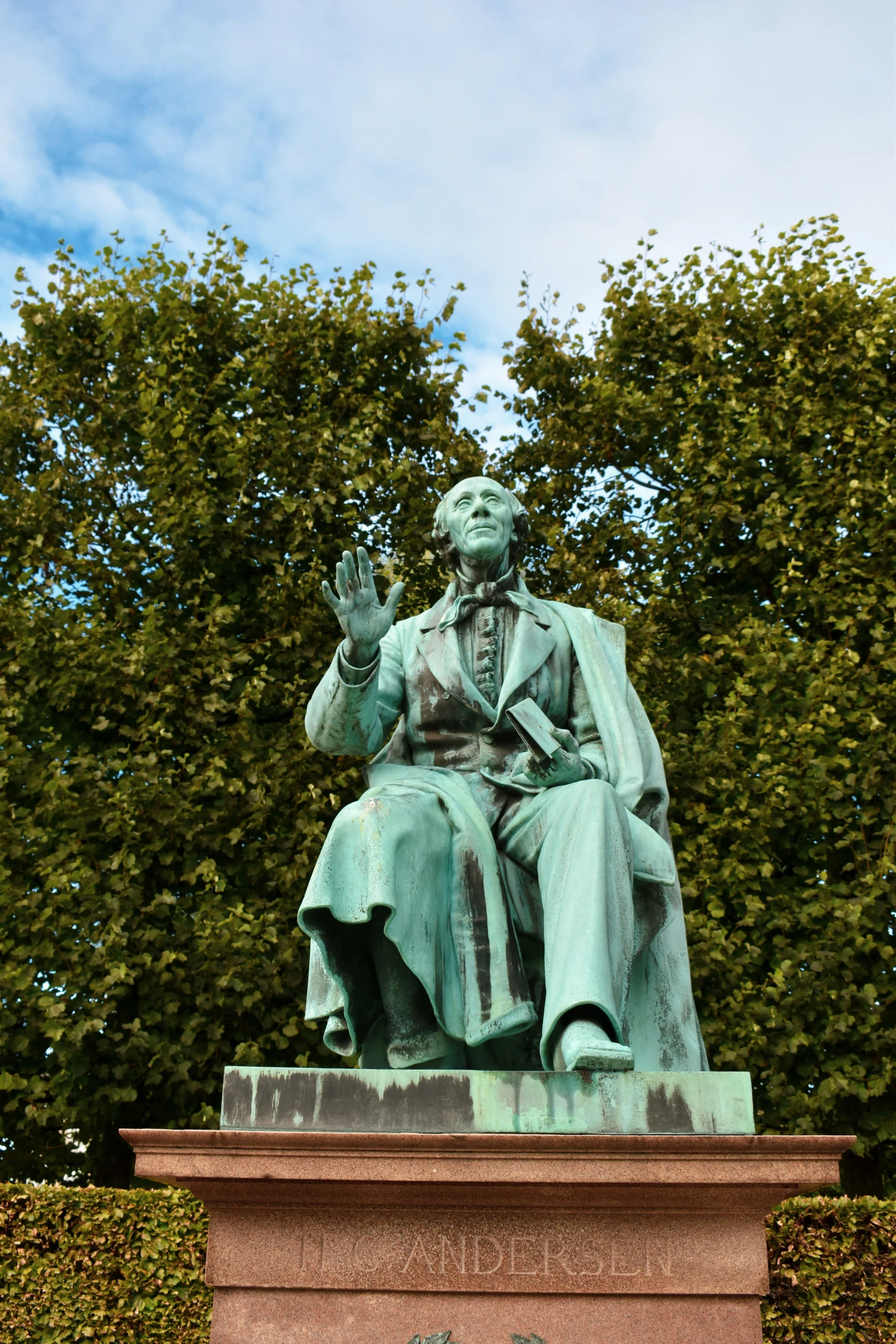 the statue of a man with a coat sits in a garden area