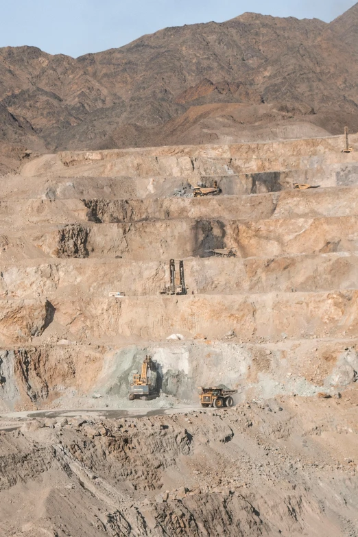 large trucks are traveling on the dirt and hill side