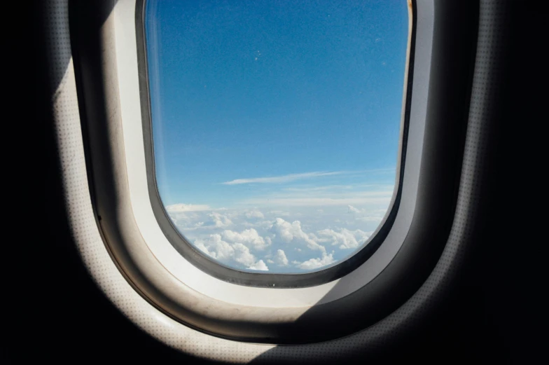 a plane window with white clouds looking out