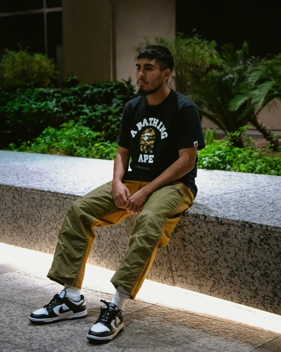 a man with his hands on his knees sitting on a ledge