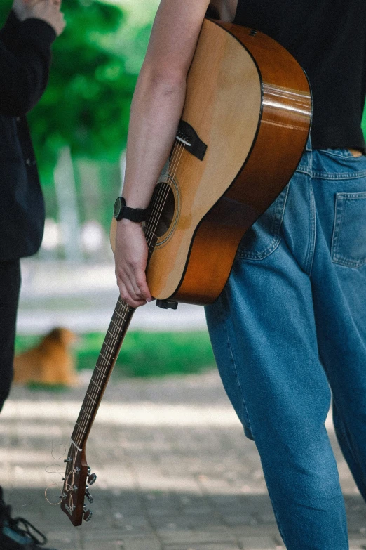 a man is walking down the street with his guitar