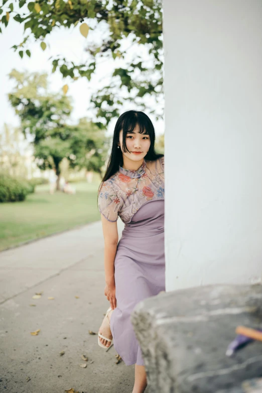 a young woman posing for a picture behind a wall