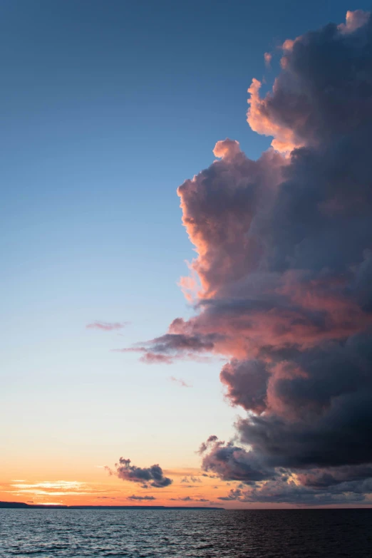 a boat floating on top of the ocean near clouds