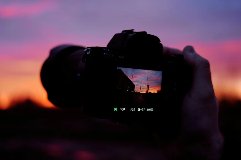 the camera with it's lens in the foreground is blurred as it turns red and the sky is purple