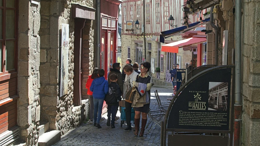 several young people are walking along a small city street