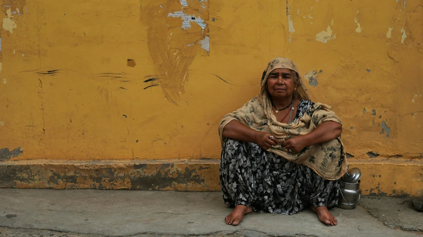 an indian woman is sitting in front of a yellow wall