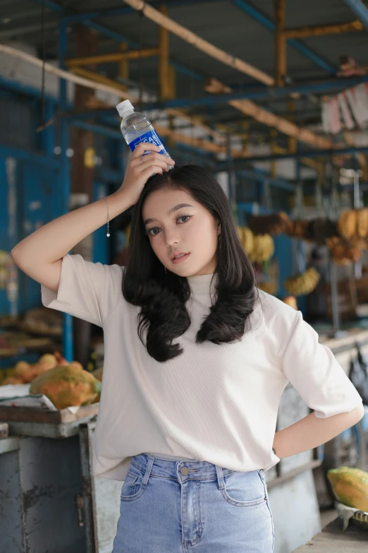 a young woman holding a bottle of water while standing next to a banana factory