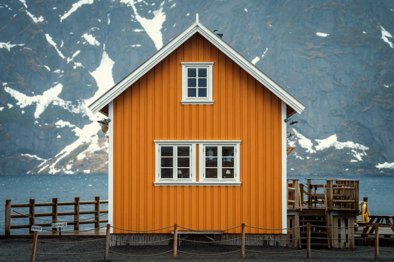 a yellow house with a small white window and a fence in front