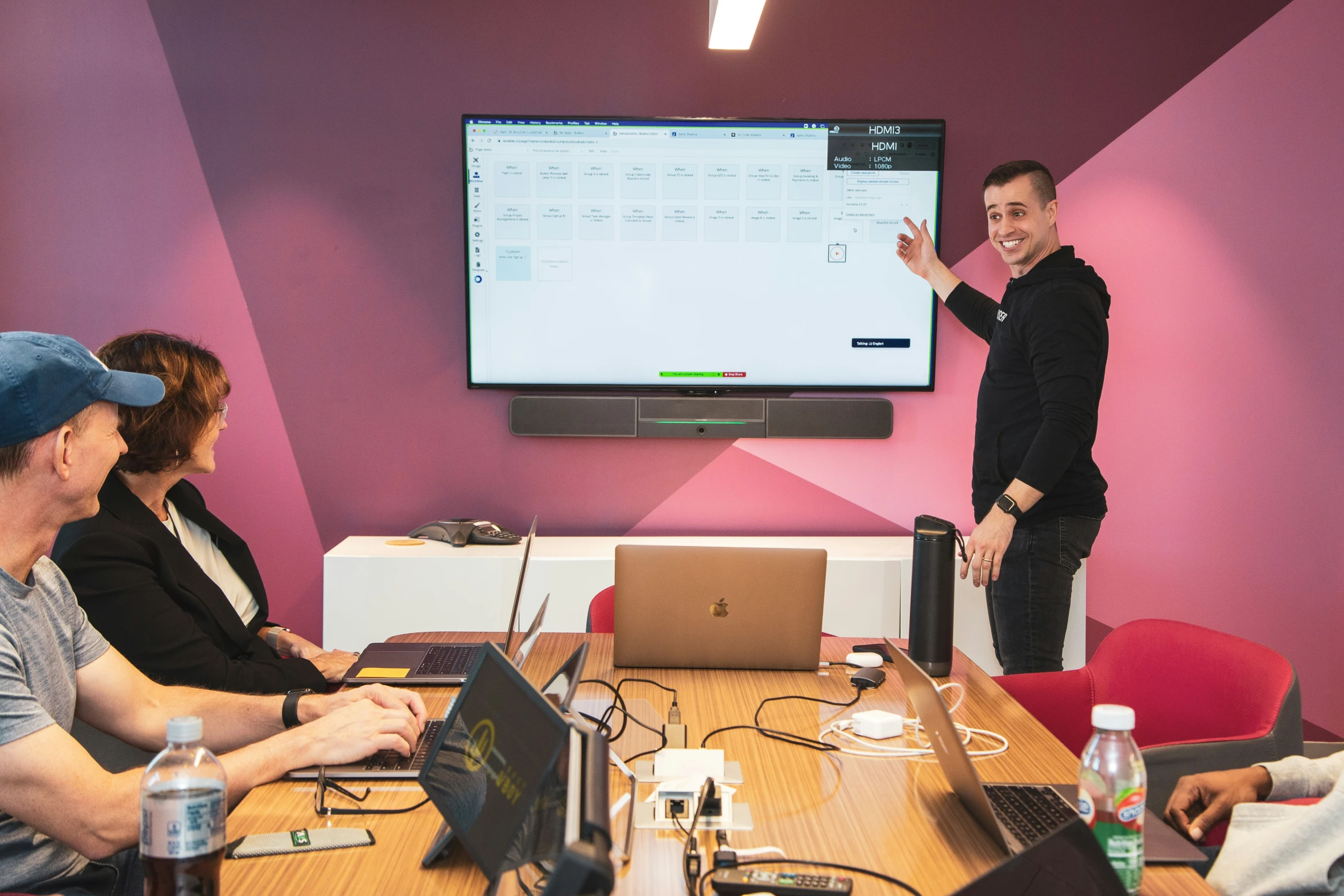 there are several people in a meeting room and a man stands by the large screen