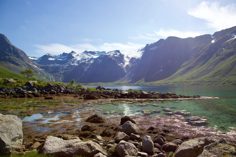 a lake with rocks and mountains near it