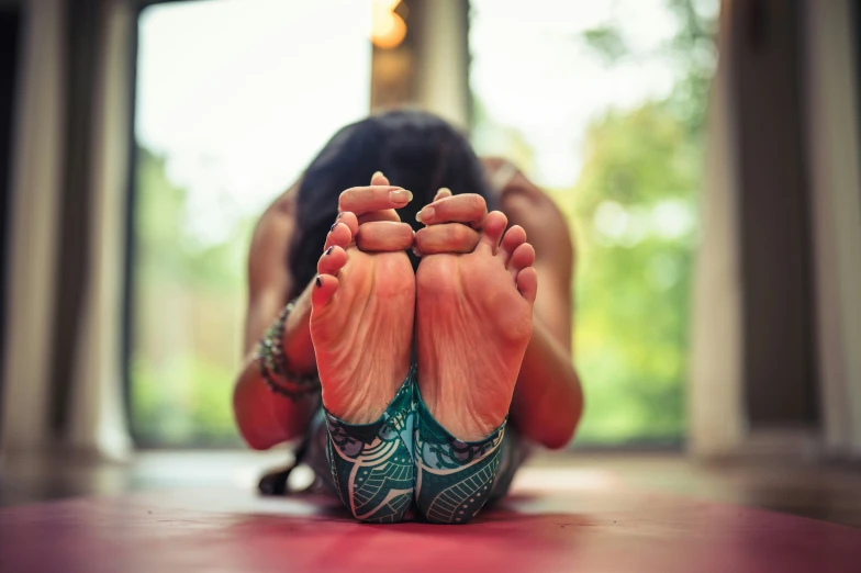 a woman is sitting on her feet and touching the floor