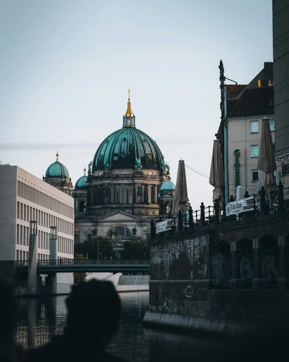 people are walking near an old bridge with a building in the background