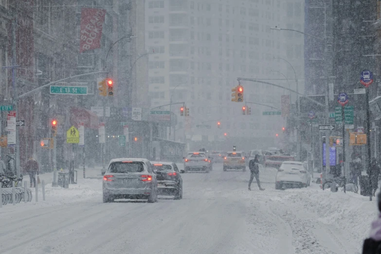 cars driving down a snow covered street in the city