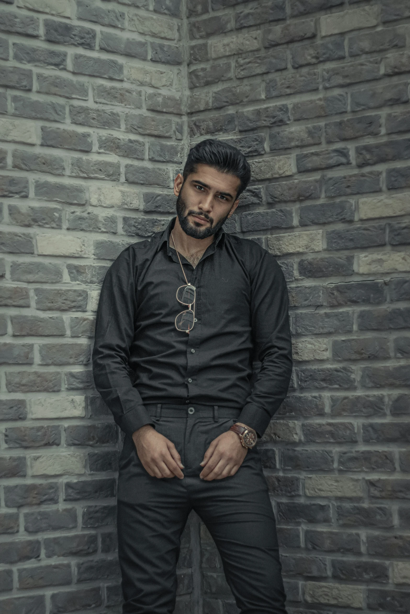 man in black shirt leaning against brick wall