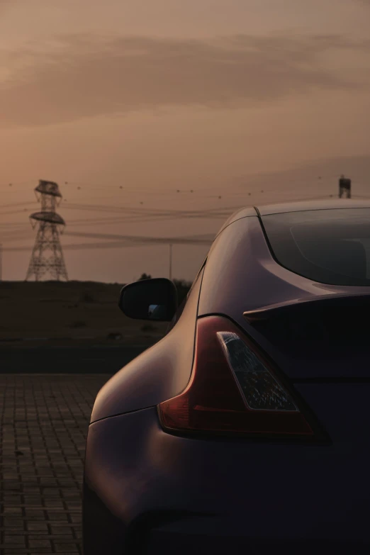 the tail end of a black car with a sunset in the background