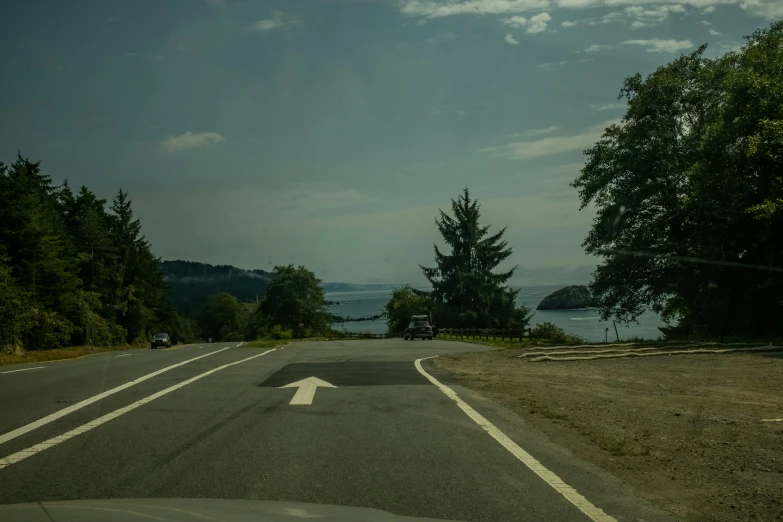 a road leading into the ocean from an empty highway