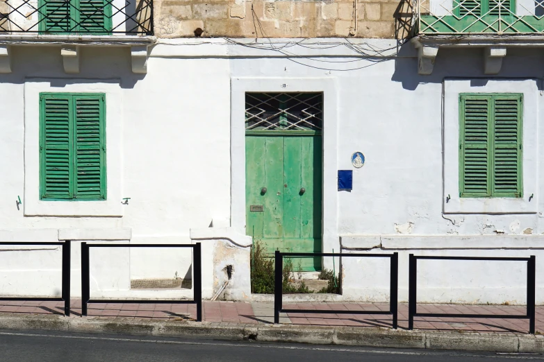 a green front door is set in between some windows