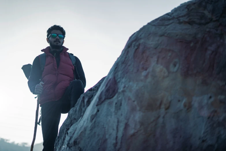 a man climbing up the side of a mountain wearing hiking gear