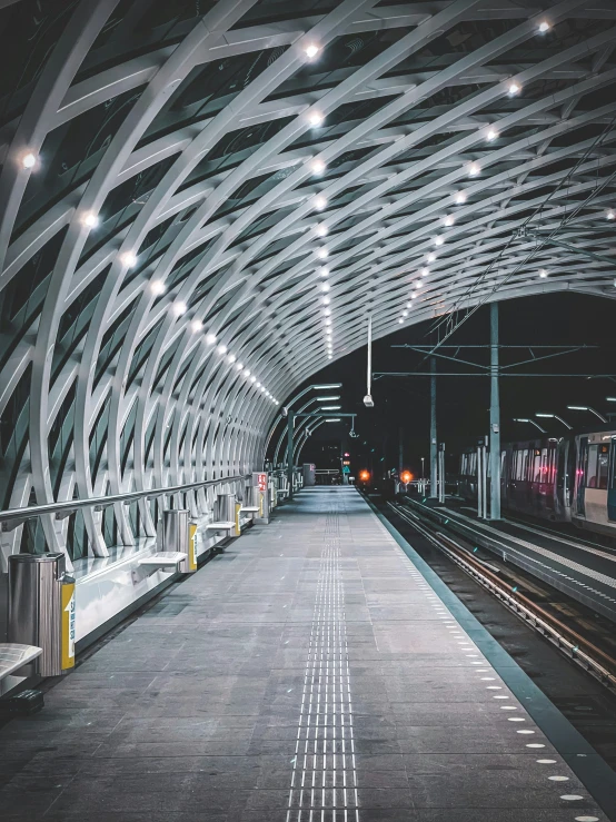 a long train station with light fixtures and an empty platform