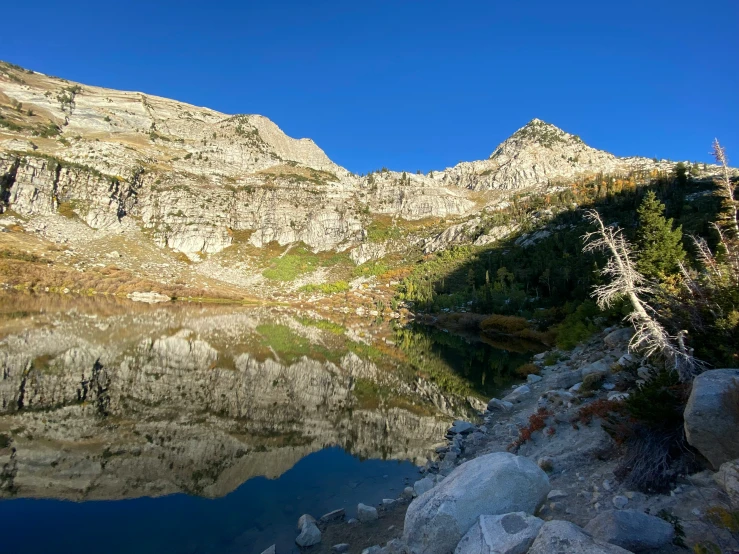 mountain side is reflected in the still water