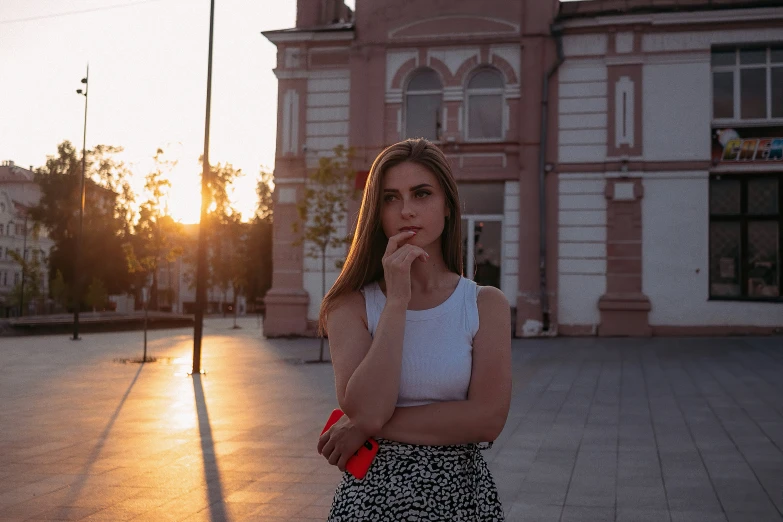 a young woman standing in front of an empty building with the sun shining down